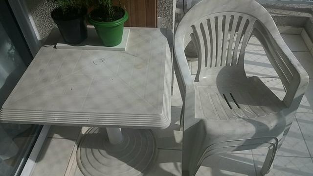 Mesa redonda e cadeiras tipo poltrona de plástico