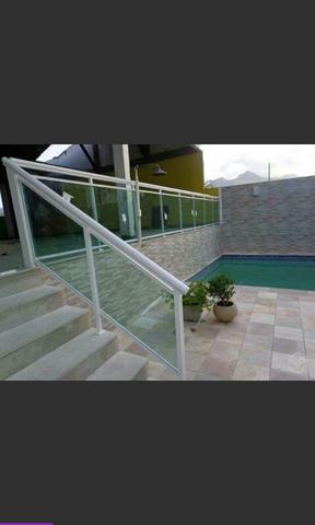 Guarda corpo e corrimão com alumínio branco e vidro verde.